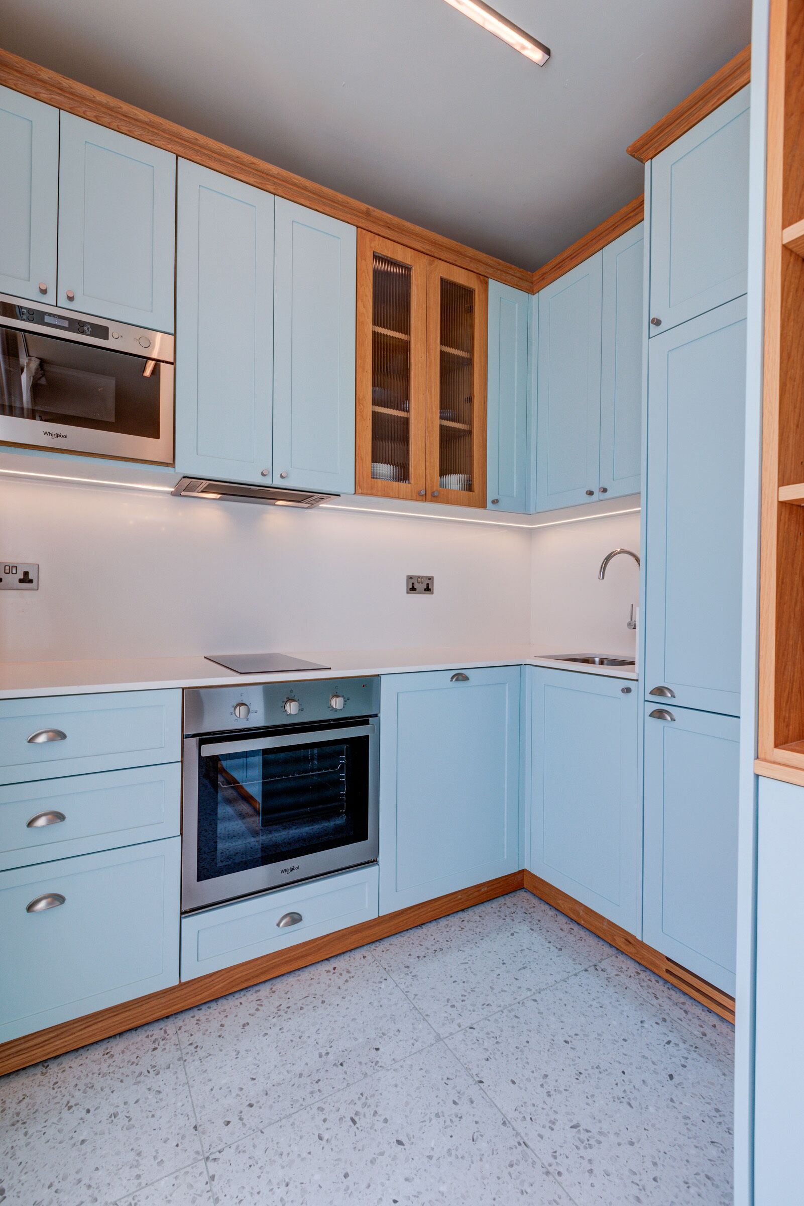 Una cucina con mobili azzurri, forno integrato e microonde.
