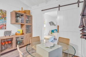 Ein modernes Wohnzimmer mit Glastisch, Korbstühlen, einem Holzkabinett mit Glastüren und einer Schiebetür im Bauernhausstil.