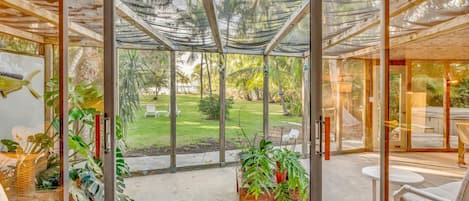 Ein modernes Zimmer mit Glastür zum Garten. Innen ein Holztisch und Stühle sowie ein Blumentopf.