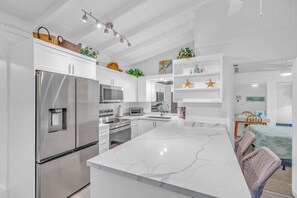 Una cocina moderna con armarios blancos, electrodomésticos de acero inoxidable y una isla de mármol.