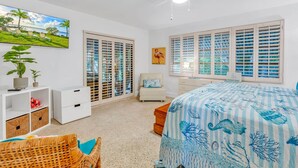 A bedroom with a large bed, a ceiling fan, a TV, a window with shutters, and a plant. - Bay Sunsets Free Kayaks/Paddleboard Jacuzzi (Key Largo)