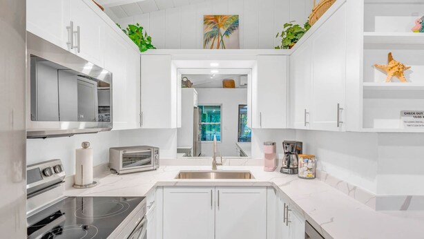 A modern kitchen with white cabinets, stainless steel appliances, and a central island. - Bay Sunsets Free Kayaks/Paddleboard Jacuzzi (Key Largo)