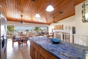 Une cuisine avec un plafond en bois, un plan de travail en marbre bleu et une vue sur l’extérieur.