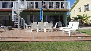 A two-story building with a balcony, outdoor seating area with white chairs and tables, and a flag. - Oceanview Marinaview Free Golf Cart Pool Pickleball (Key Largo)
