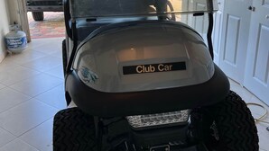 A golf cart with a 'Club Car' label in a garage. - Oceanview Marinaview Free Golf Cart Pool Pickleball (Key Largo)