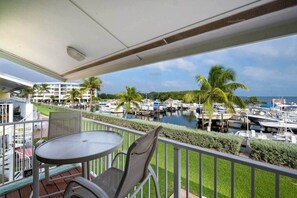 Ein Balkon mit Tisch und Stühlen mit Blick auf eine Marina, in der Boote und Palmen zu sehen sind.