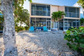 A two-story building with a balcony, a pool, and a gravel driveway.