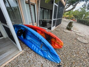 Deux kayaks sont garés devant un bâtiment, sur un sol recouvert de gravier.