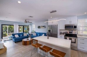 Une cuisine moderne dotée d’un îlot central, de tabourets de bar et d’un coin repas avec un canapé bleu.