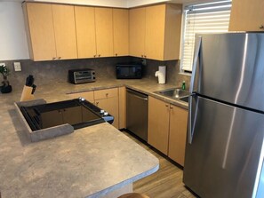 A modern kitchen with wooden cabinets, a built-in stove, a microwave, and a stainless steel refrigerator. - Lagoon View Free Kayaks Pool Playground Pickle Ball (Key Largo)
