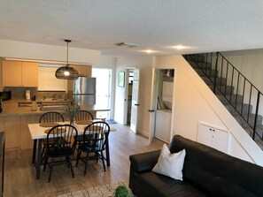 A modern kitchen with a dining area, a black leather sofa, and a staircase. - Lagoon View Free Kayaks Pool Playground Pickle Ball (Key Largo)