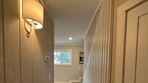 A hallway with wooden paneling, a light fixture, a window, and a door.