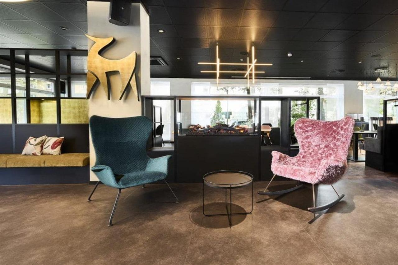 A modern lobby with a seating area, a reception desk, and a large abstract sculpture.