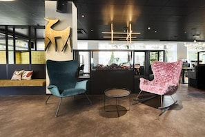 A modern lobby with a seating area, a reception desk, and a large abstract sculpture.