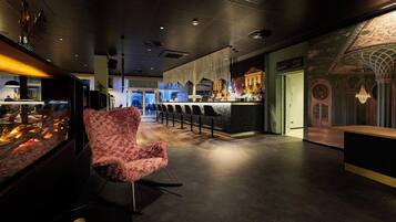 A modern interior with a bar area, a patterned chair, and a decorative ceiling.