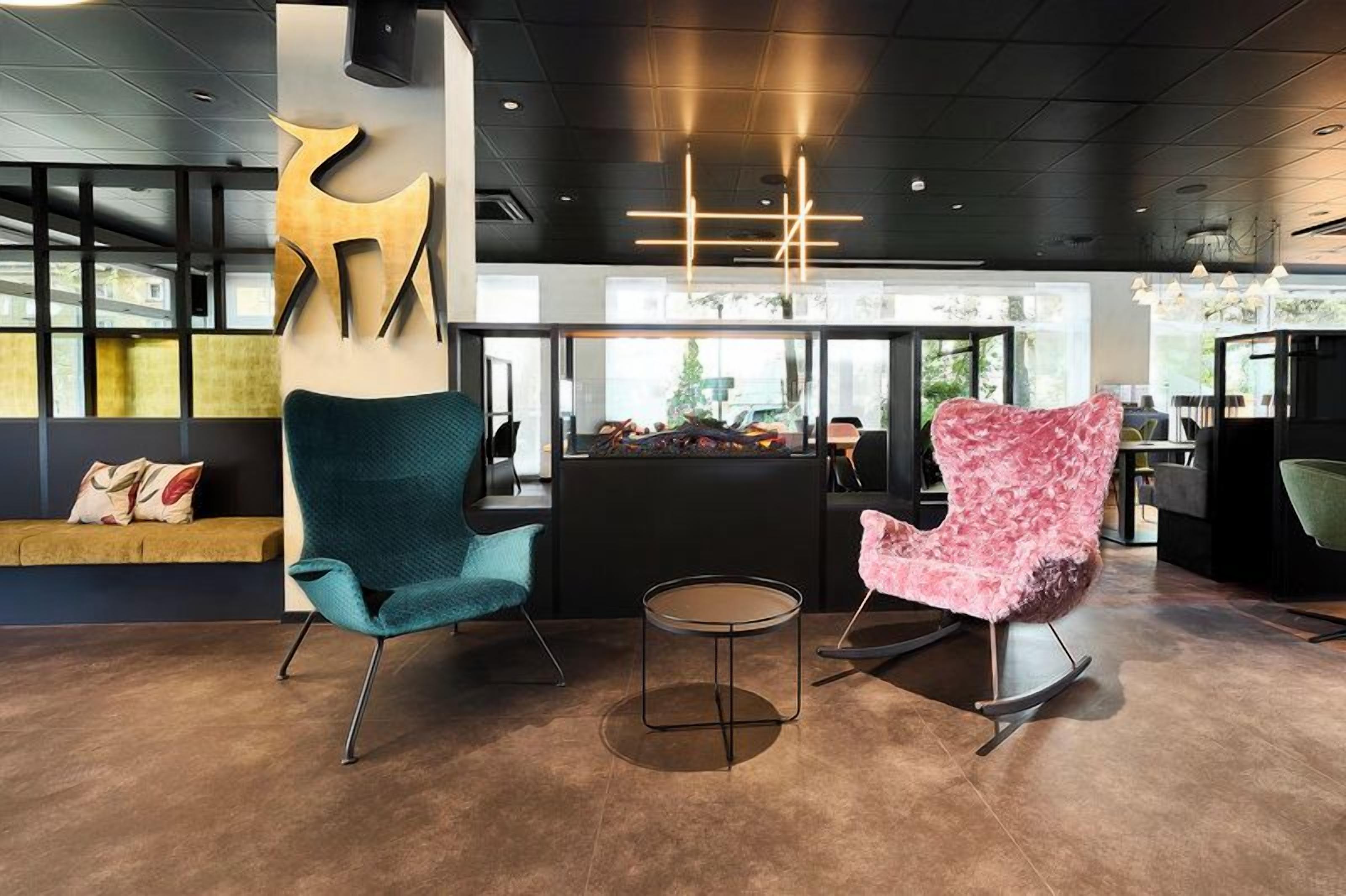 A modern interior with two chairs, a round table, and a reception area with a counter.