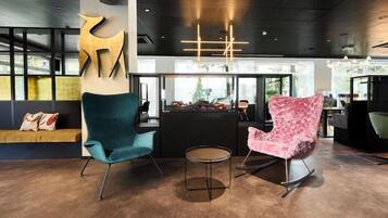 A modern interior with two chairs, a round table, and a reception area with a counter.