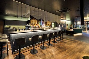 A modern bar area with a long counter, multiple stools, and a decorative mural on the wall. - Top Hotel Rhoenkitz Bad Kissingen (Bad Kissingen)