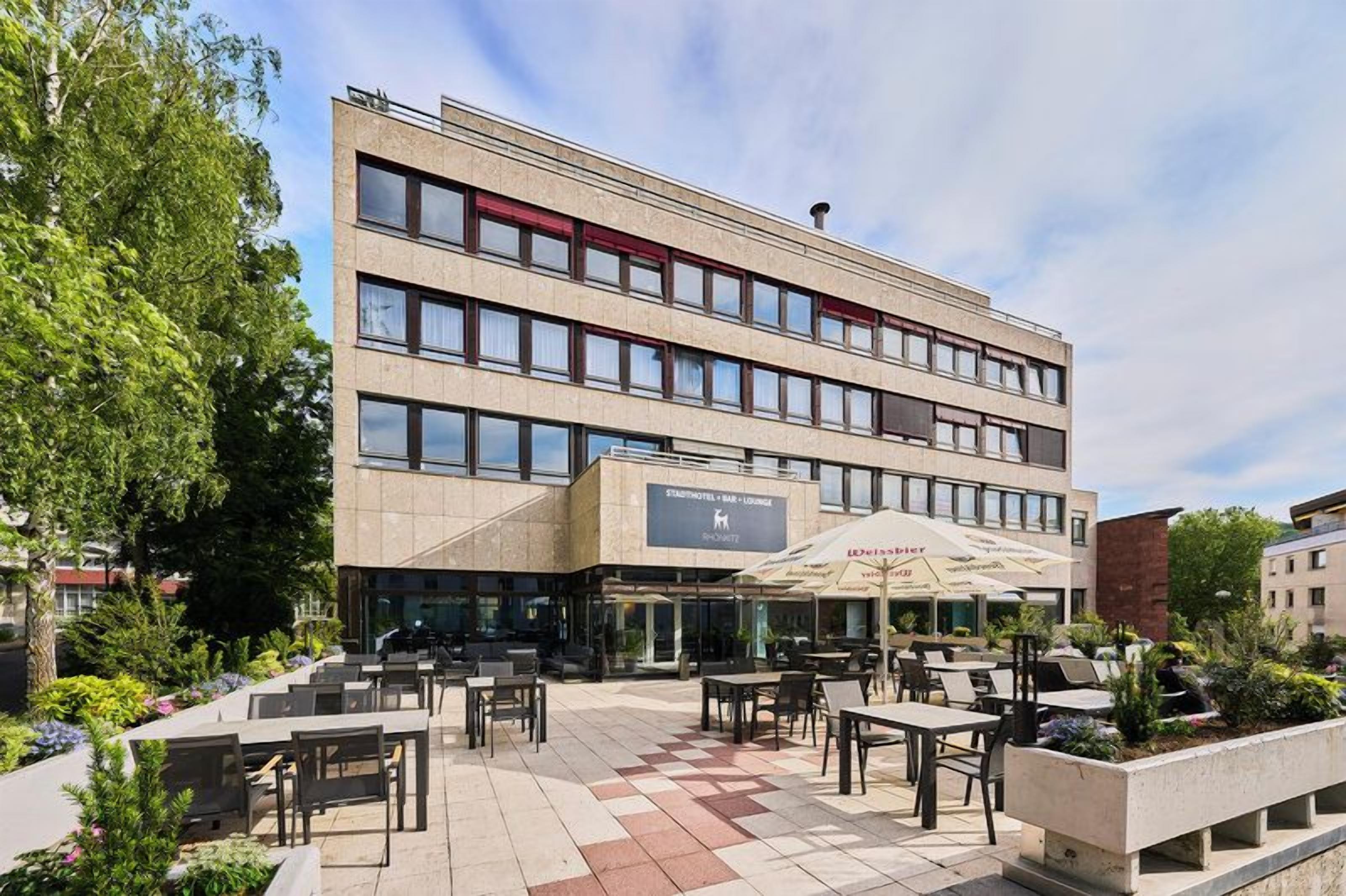 A multi-story hotel with outdoor seating and a garden area.