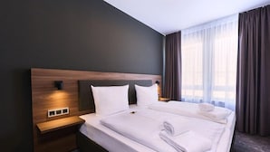 A modern hotel room with a large bed, a bedside table, and a nightstand. - Top Hotel Rhoenkitz Bad Kissingen (Bad Kissingen)