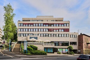 Un edificio de varios pisos con techo plano, ventanas amplias y una escalera que conduce a la entrada.