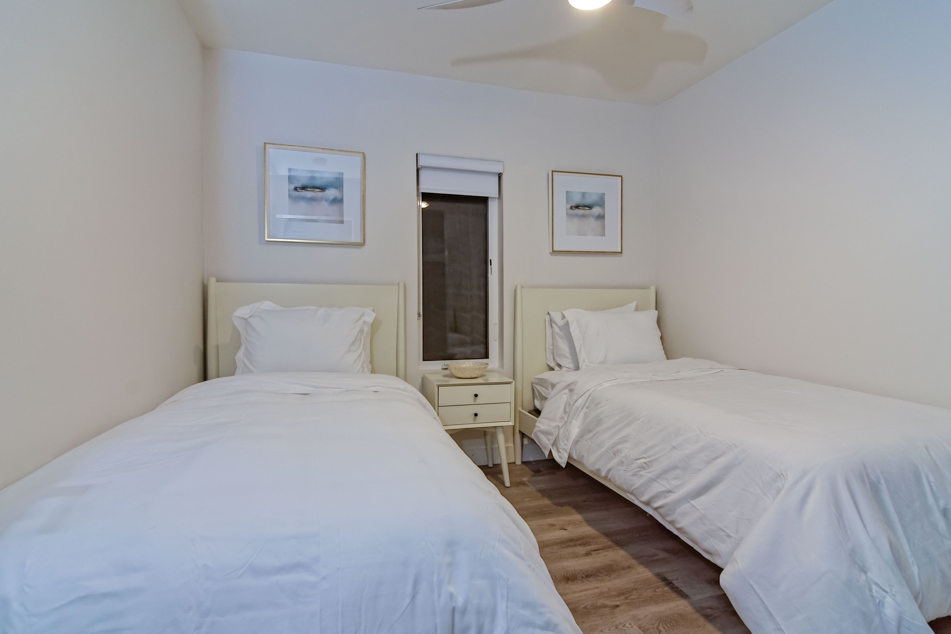 A room with two single beds, a small bedside table with a lamp, and a mirror.