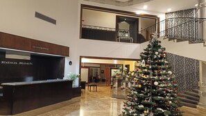A reception desk with a nameplate, a Christmas tree, and a staircase with a railing.