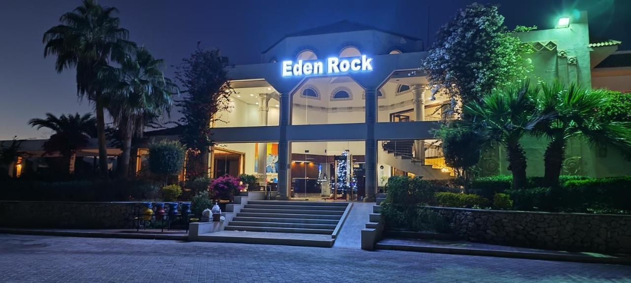 Ein Hotel Eingang mit einem Schild mit der Aufschrift 'Eden Rock' und einer Treppe, die zum Eingang führt.