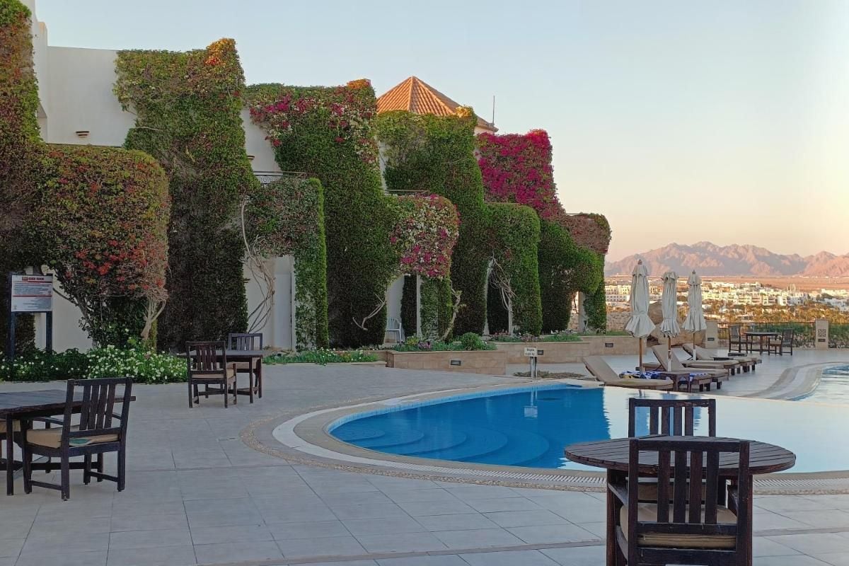 Un espace aménagé au bord de la piscine, comprenant une piscine, des chaises longues et des tables.