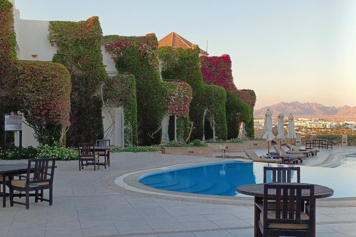 A poolside area with a swimming pool, lounge chairs, and tables.