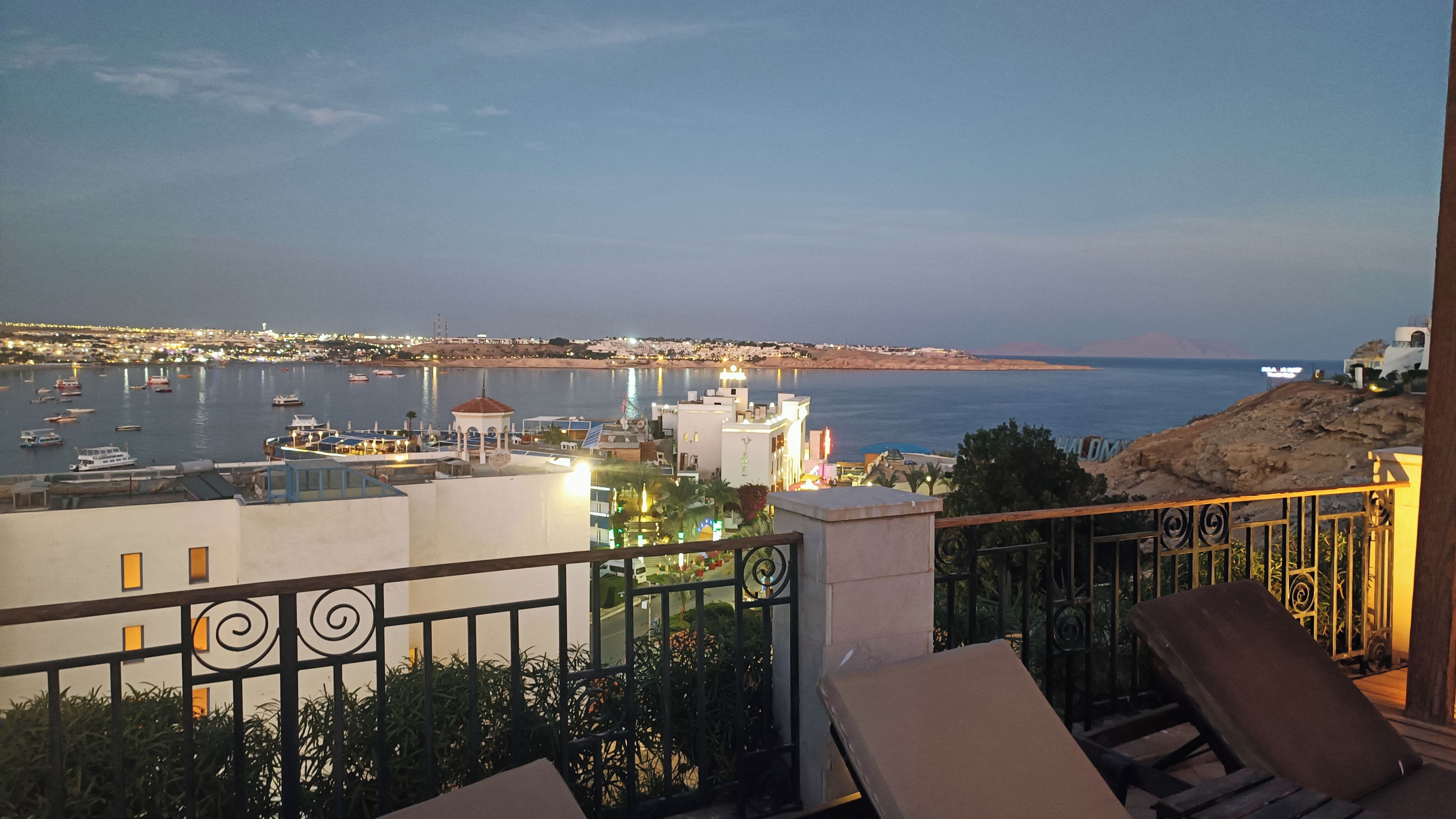 Varanda com vista para uma marina e paisagem urbana ao anoitecer.