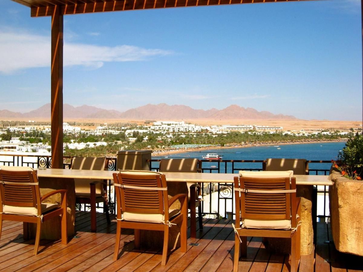 A wooden deck with outdoor seating overlooking a coastal view with mountains in the distance.
