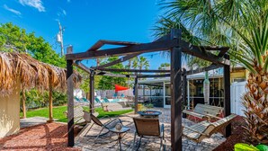 Un espacio de descanso al aire libre con techo, una pérgola, un brasero y sillones de lounge.