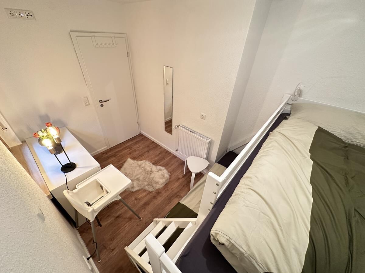Une petite pièce, de taille modeste, comprenant un lit superposé, un lavabo blanc, un miroir et un radiateur.