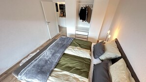 A bedroom with a bed, a closet, and a kitchenette. - FRITZ - Haus Sonnenblick (Diemelsee)