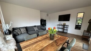 A modern living room with a wooden dining table, grey sofa, and a vase of tulips. - FRITZ - Haus Sonnenblick (Diemelsee)
