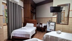Ein Hotelzimmer mit zwei Betten, einem Schreibtisch, einem Sessel, einem Fernseher und einem Spiegel.