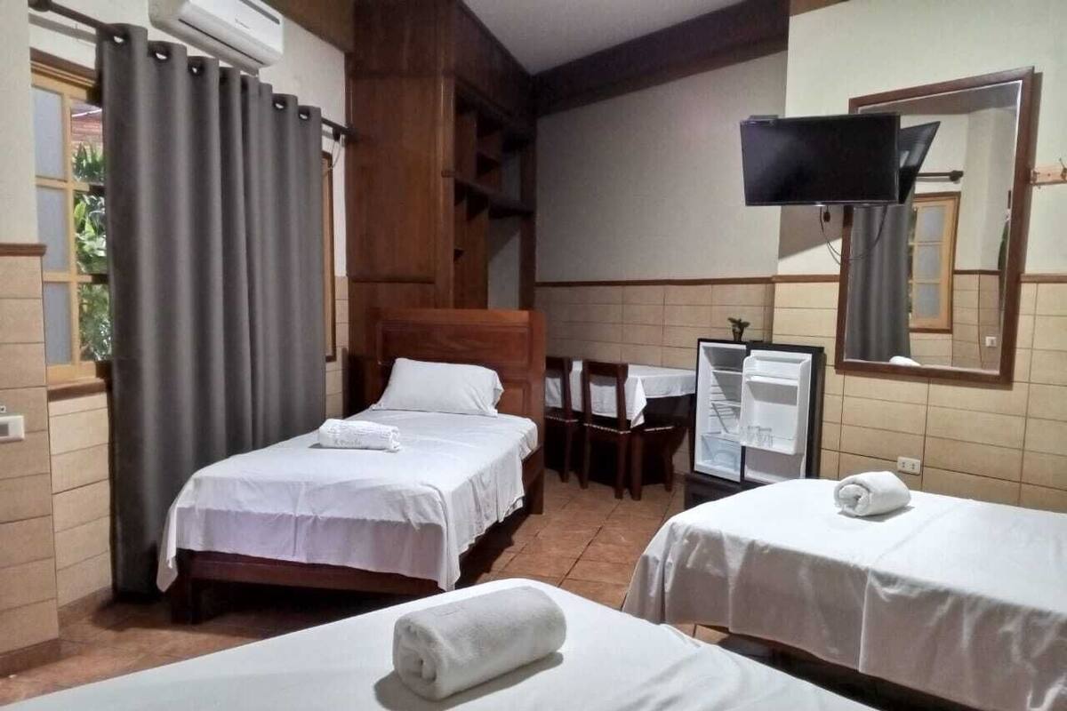 Habitación de hotel con dos camas, un escritorio, una silla, un televisor y un espejo.