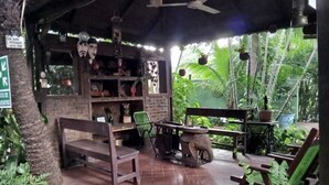 Eine Terrasse im Freien mit Holzmöbeln, einer Steinwand und Kübelpflanzen.