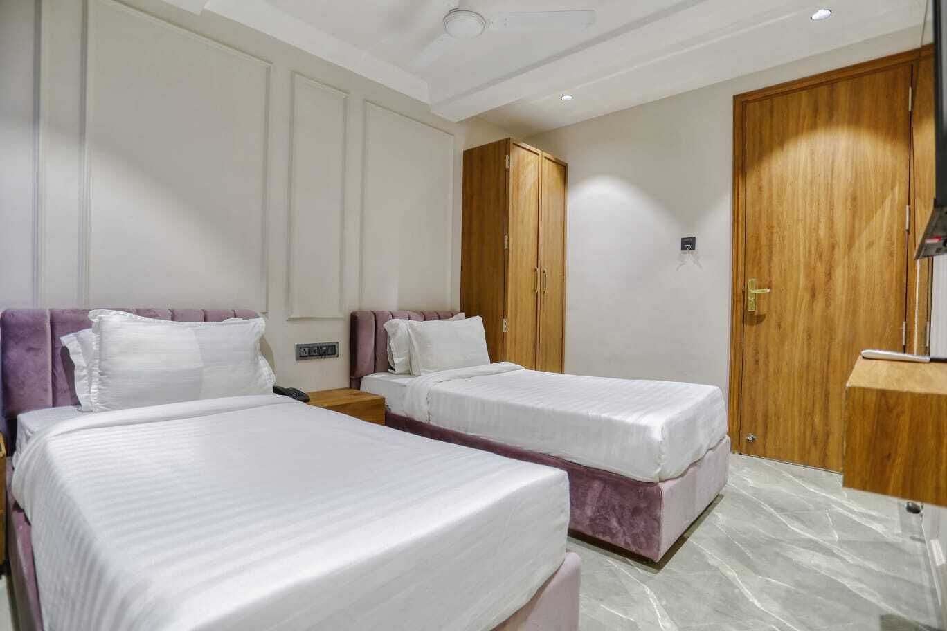 Habitación de hotel con dos camas, un armario de madera, una mesita y una mesita de noche.