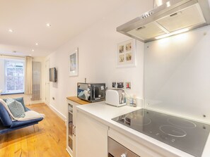 A modern kitchen with a built-in stove, microwave, and toaster. There is a window with curtains and a view of a brick building outside.