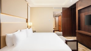 Une chambre d’hôtel avec un grand lit, un téléviseur fixé au mur, un bureau et une chaise.