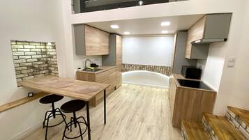 A modern kitchen with a built-in dishwasher, a dining area with stools, and a stone accent wall.
