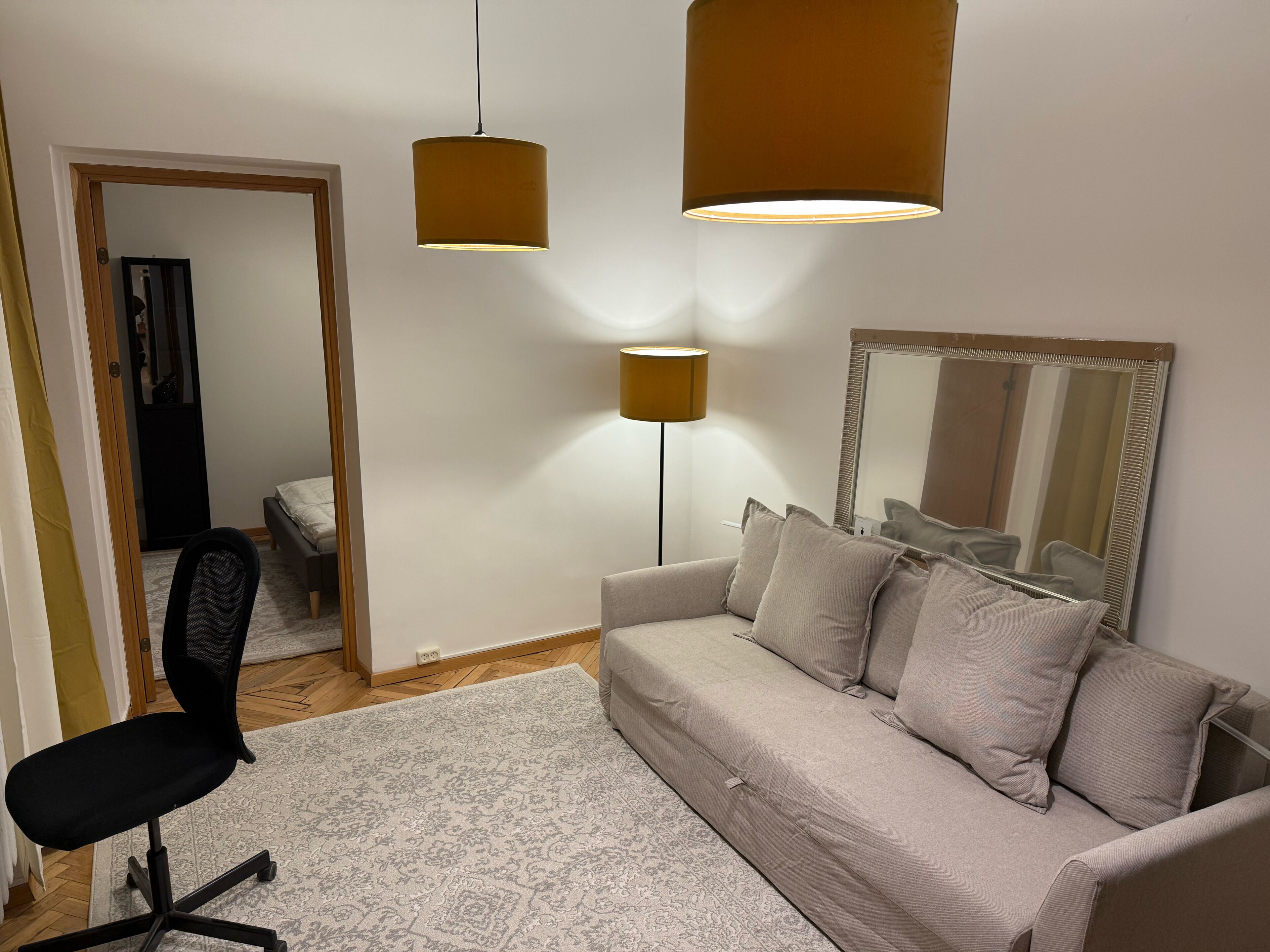 Una sala de estar moderna con un sofá, un sillón, una lámpara de pie y un espejo en la pared.