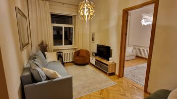 A living room with a sofa, a television, a wooden cabinet, and a radiator.