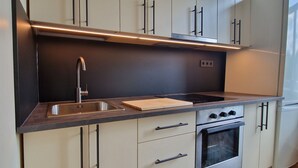 Una cocina moderna con un lavamanos de acero inoxidable, una tabla de cortar de madera y un horno empotrado.