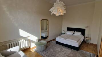 Een slaapkamer met een bed, een radiator, een spiegel, een nachtkastje en een hanglamp.