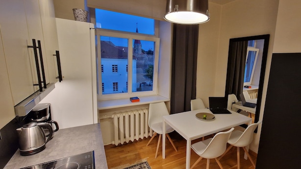 Una cocina compacta con ventana, una mesa blanca y un refrigerador negro.