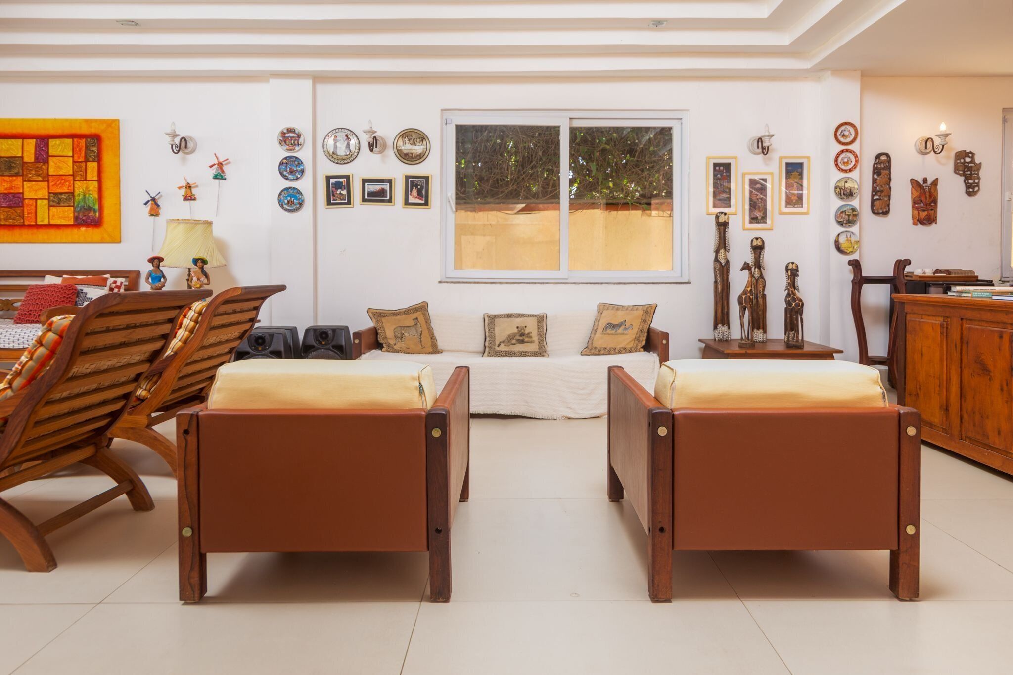 A room with two wooden beds, a sofa, and a dining table. There are wall decorations and a window with a view.