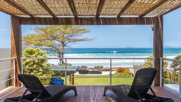 A balcony with wicker chairs, a view of the ocean, and a tree. - Mansão Pé na Areia de Geribá com 6Suítes (Búzios)